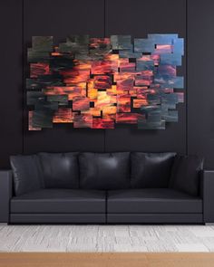 an abstract painting on the wall above a black couch in a living room with wood flooring