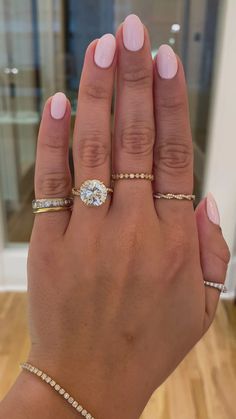 a woman's hand with three different rings on her fingers and one is holding the other