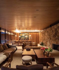 a living room filled with furniture and a fire place next to a wall covered in stone