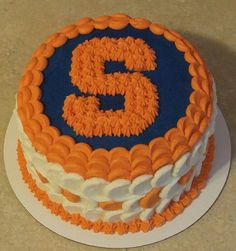 an orange and blue cake with the number five on it's icing is sitting on a table