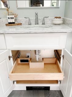 an open drawer in the middle of a bathroom sink