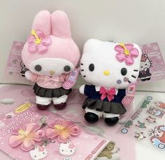 two hello kitty stuffed animals sitting next to each other on a table with stickers