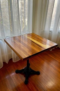 a wooden table sitting on top of a hard wood floor in front of a window