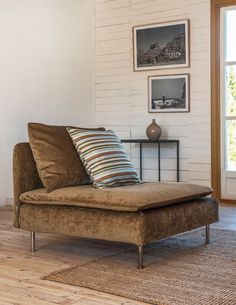 a brown couch sitting on top of a hard wood floor next to a white brick wall