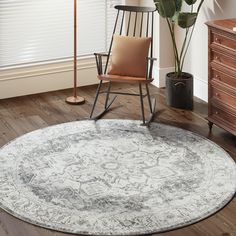 a white and gray rug in a living room with a rocking chair, potted plant and lamp