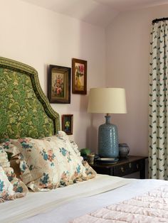 a green headboard on a bed in a room with pink walls and floral pillows