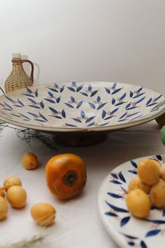 two plates with fruit on them sitting on a table next to an orange and some other fruits