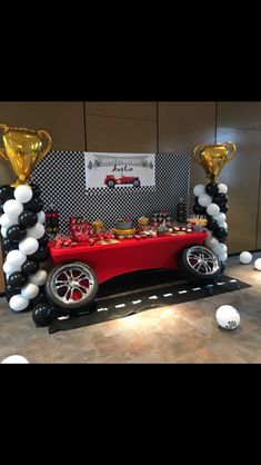 a red car with balloons on it and some black and white balls in the air