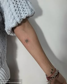 a woman's arm with a small flower tattoo on the left forearm and wrist