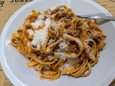 a white plate topped with pasta covered in sauce and parmesan cheese