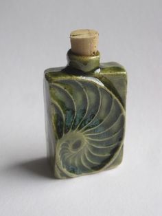 a green and white bottle with a cork top in the shape of an ammonite shell