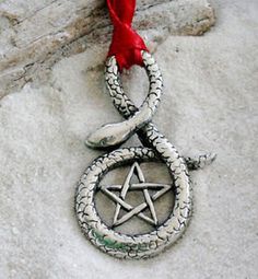 an ornament with a pentagram and star on it hanging from a red ribbon