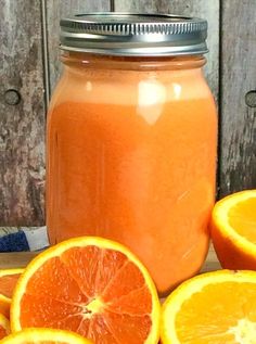 an orange is sitting on a table next to some sliced oranges and a mason jar