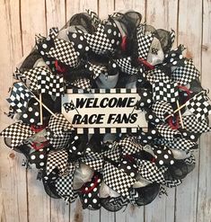 a welcome race fan wreath hanging on the side of a wooden door with black and white checkered mesh