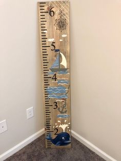 a tall wooden growth chart with blue whale and sailboat on it's side