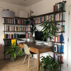 a home office with bookshelves full of books and plants on the desk area