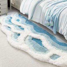 a blue and white rug on the floor next to a bed