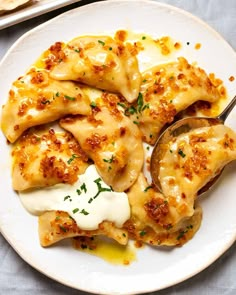 a white plate topped with ravioli covered in cheese and sauce next to a fork