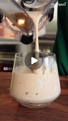 someone pouring milk into a glass on top of a wooden table