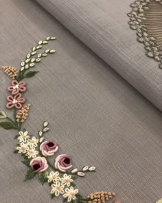 a close up of a piece of cloth with flowers and leaves embroidered on the side