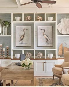 a living room filled with furniture and paintings on the wall next to a wooden table