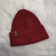 a red knitted hat laying on top of white fur