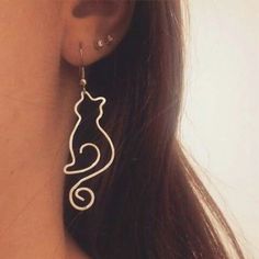 a close up of a person's ear with a cat shaped earrings on it