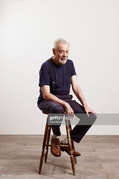 an elderly man sitting on a stool in front of a white wall stock photo getty images