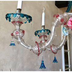 a chandelier hanging from the ceiling with colorful glass flowers and tassels