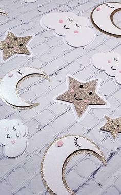 stars and moon cutouts on a white brick wall with gold glitters in the shape of clouds