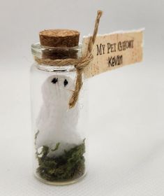 a glass jar filled with moss and a small white bird in it's beak