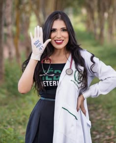 a woman with her hand up in the air while wearing a white jacket and black dress