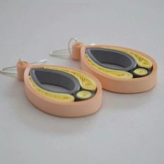 two pairs of earrings with yellow and black designs on the front, sitting on a white surface