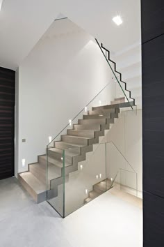 a staircase with glass railing and wooden handrail