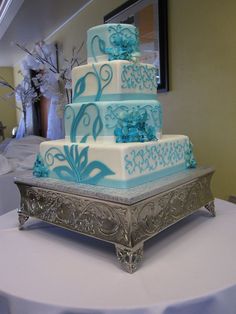 a blue and white wedding cake sitting on top of a silver tray at a table