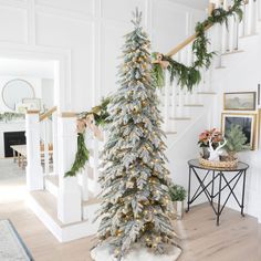 a decorated christmas tree in the middle of a living room with stairs and banisters