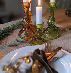 the table is set with two candles and three dishes, one has silverware on it