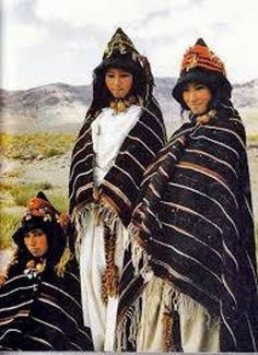 three women dressed in black and white are posing for a photo with mountains in the background