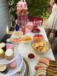 a table topped with cupcakes, watermelon slices and other food items