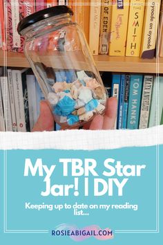 a person holding up a jar filled with small objects in front of a bookshelf