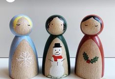 three wooden peg dolls are standing next to each other with snowmen painted on them