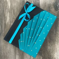 a blue gift box wrapped in black paper with white polka dots and a turquoise ribbon