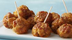 several meatballs with toothpicks on a white plate next to blue tablecloth