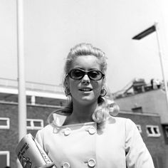 a black and white photo of a woman in sunglasses holding a can with her right hand