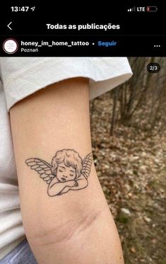 a small tattoo on the arm of a woman with an angel in her arms,