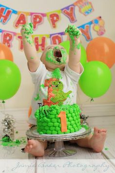 a baby sitting on top of a cake covered in green frosting