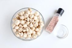 a glass bowl filled with chickpeas next to a salt and pepper shaker