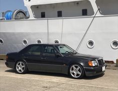 a black mercedes benz parked in front of a cruise ship with the word's name on it