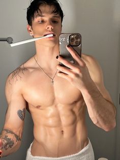 a shirtless man taking a selfie with an electronic toothbrush in his mouth