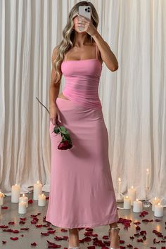 a woman in a pink dress taking a selfie with her cell phone while surrounded by rose petals